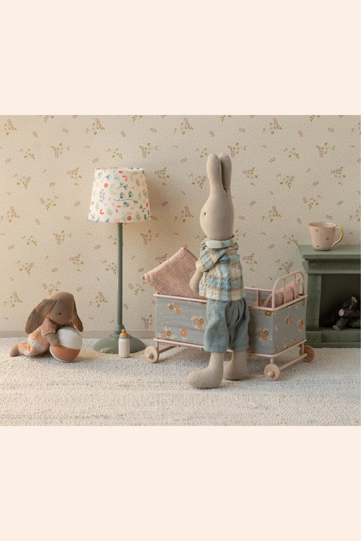 Maileg - Cot Bed Micro - Powder - Strawberries & Cream - Ingrid Lewis - Designer 
Children's room with plush toys, a lamp, and a crib against a floral wallpaper.