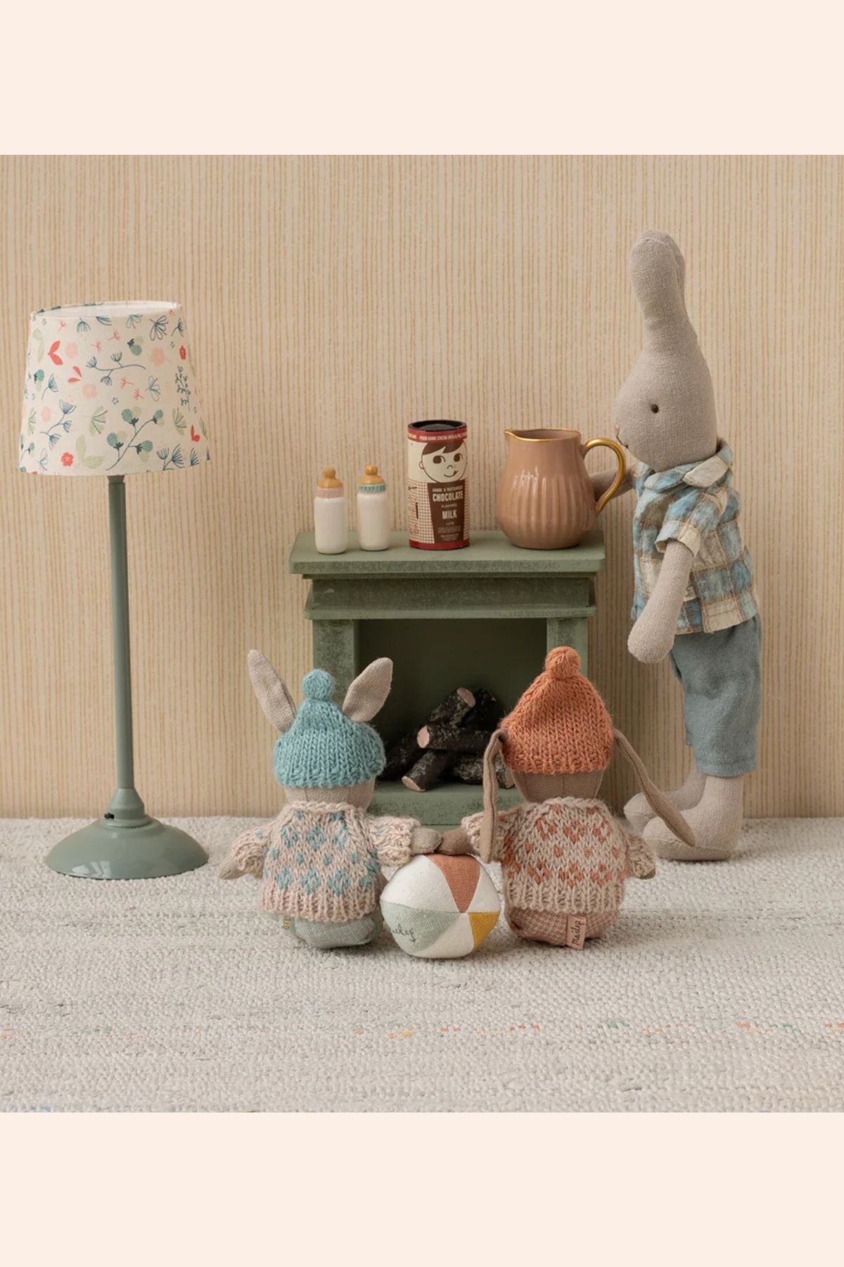 Three toy rabbits in a room with a lamp and small table.