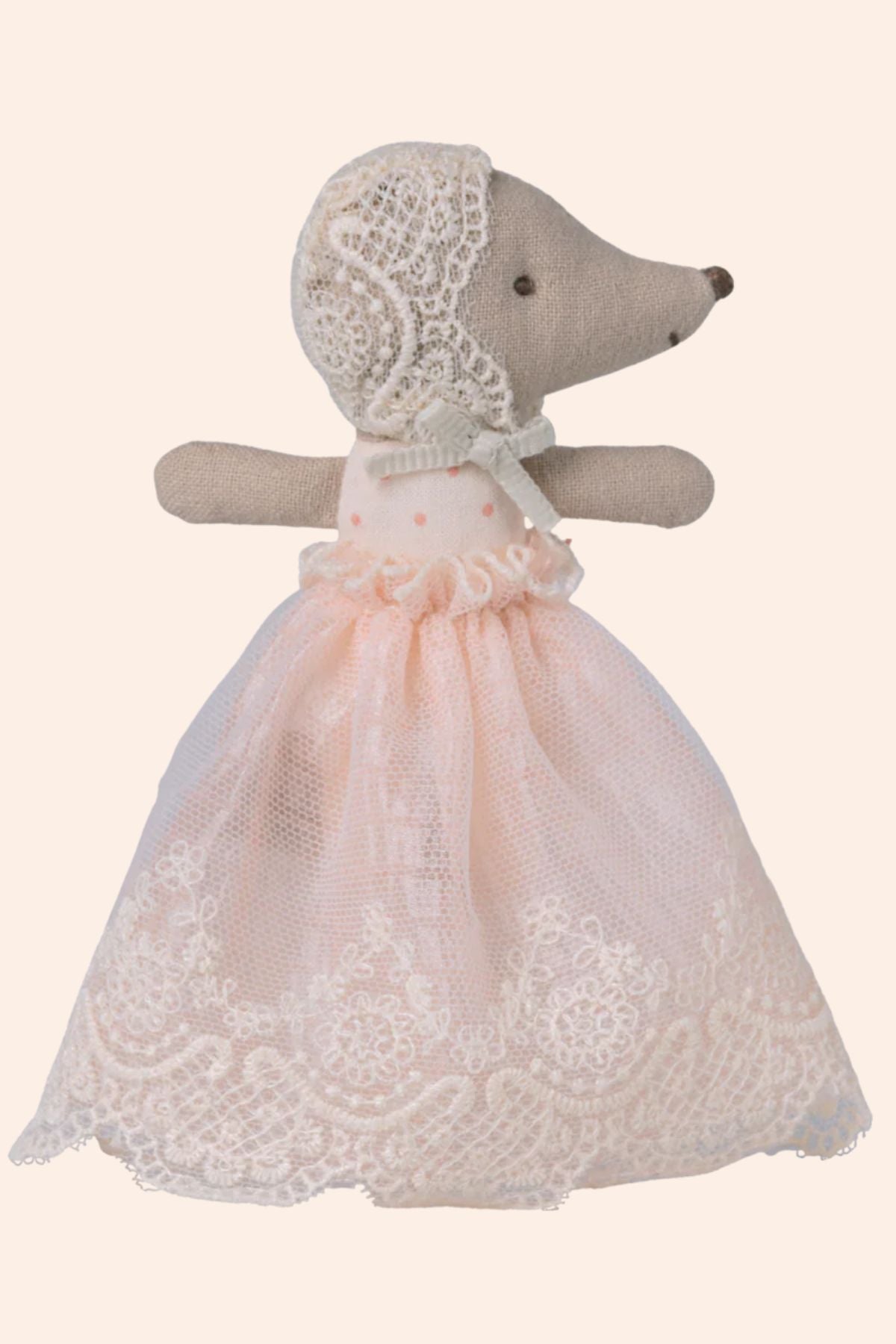 Teddy bear toy dressed in a pink lace dress on a beige background
