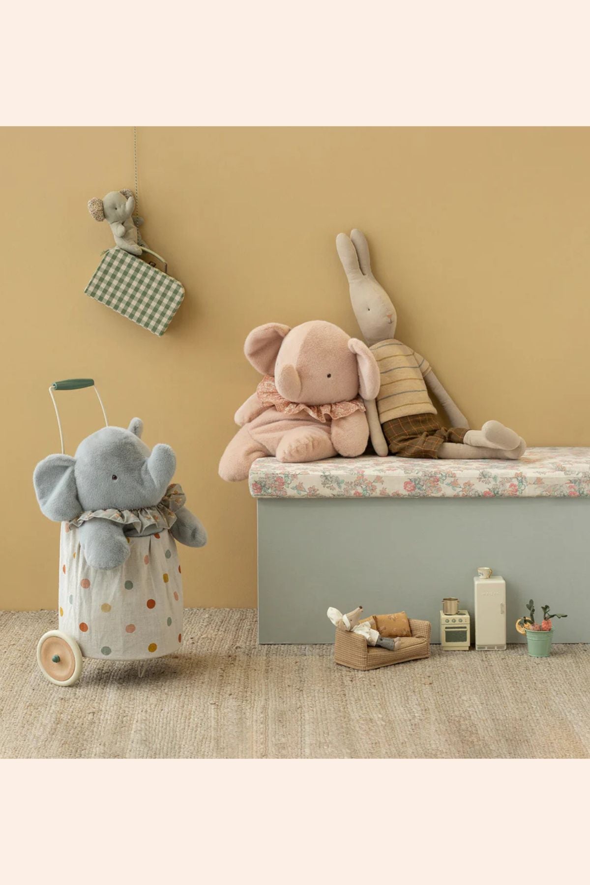 Children's room with plush toys including elephants and a rabbit on a shelf against a beige wall.