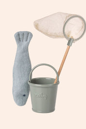 Gray toy fish, bucket, and net on a light beige background