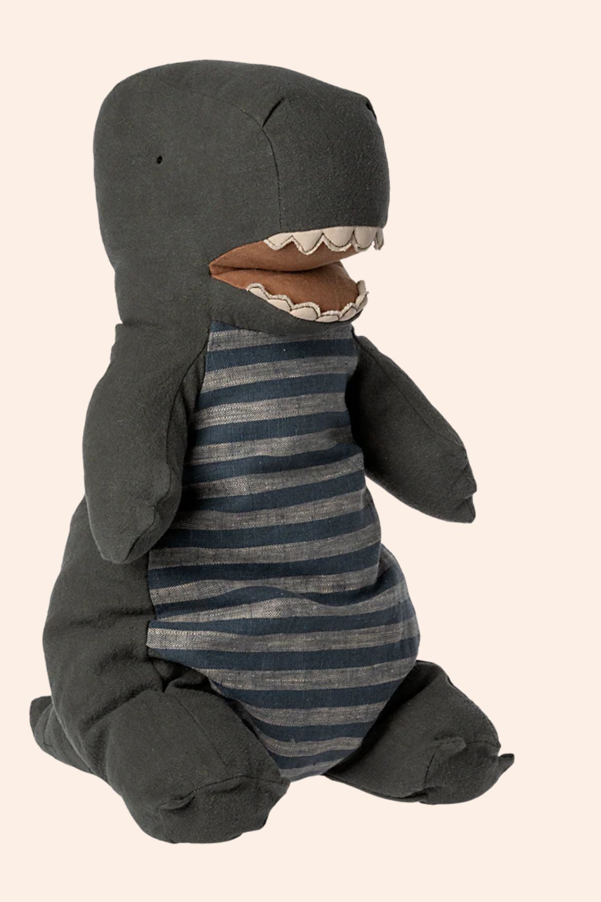 Plush toy shark in a striped outfit on a beige background