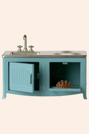 Teal vanity with sink and open cabinet on a beige background