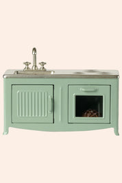 Mint green kitchen sink unit with a small window on a white background
