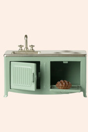 Vintage-style kitchen sink with cabinet and decorative items on a light green background