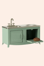 Green metal cabinet with sink and open door on a beige background