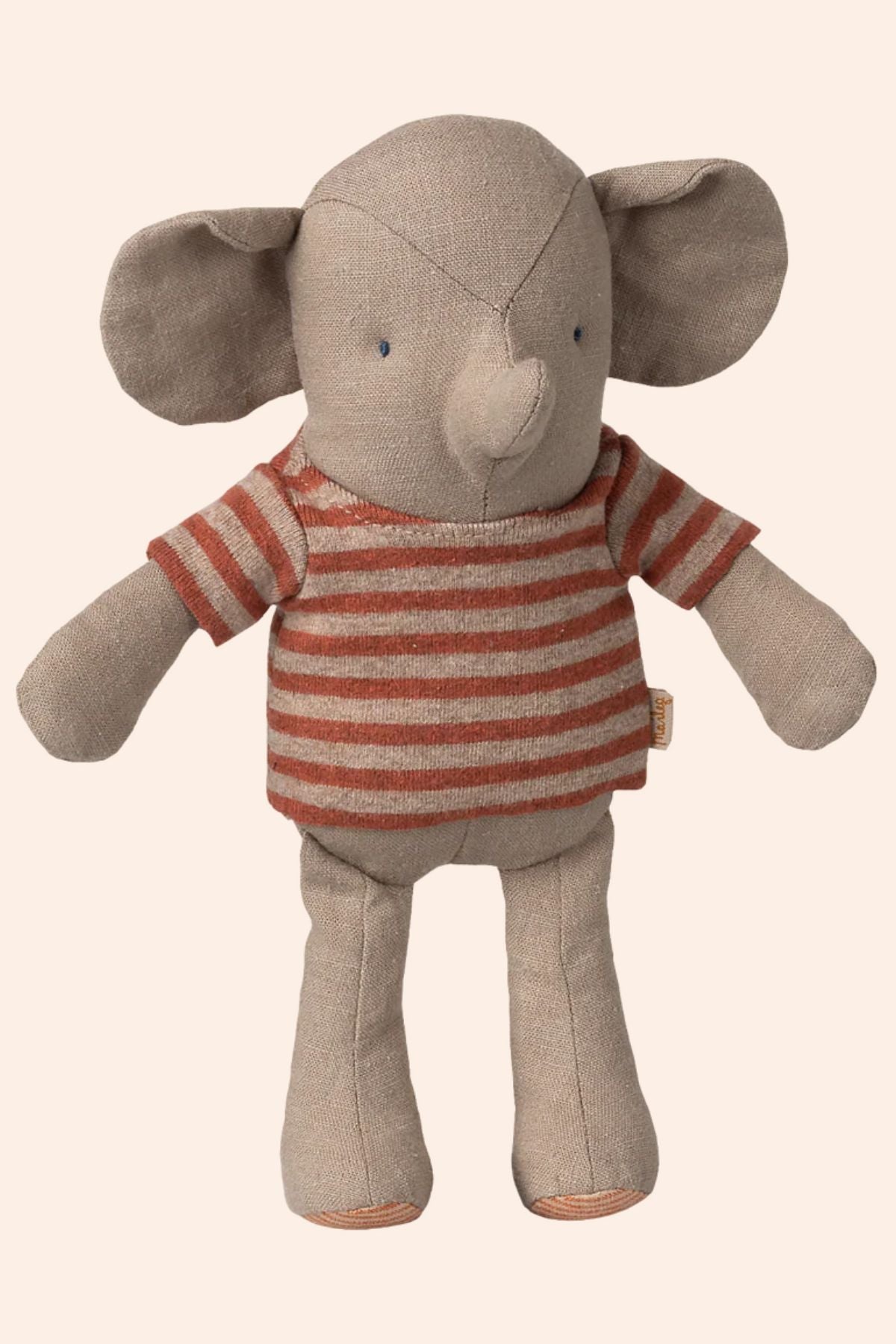Stuffed elephant toy wearing a striped shirt on a beige background