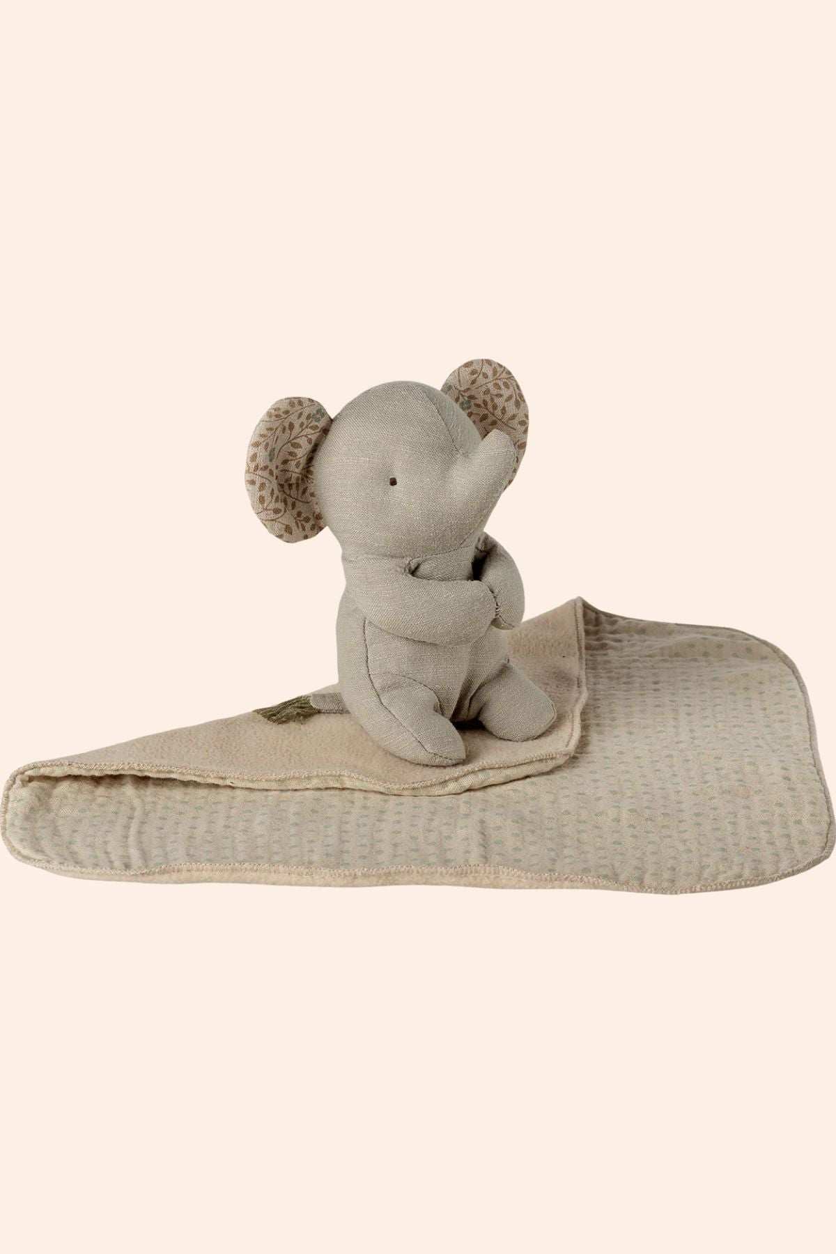 Stuffed elephant toy with a blanket on a beige background