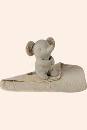 Stuffed elephant toy with a blanket on a beige background