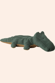 Green plush toy alligator on a beige background