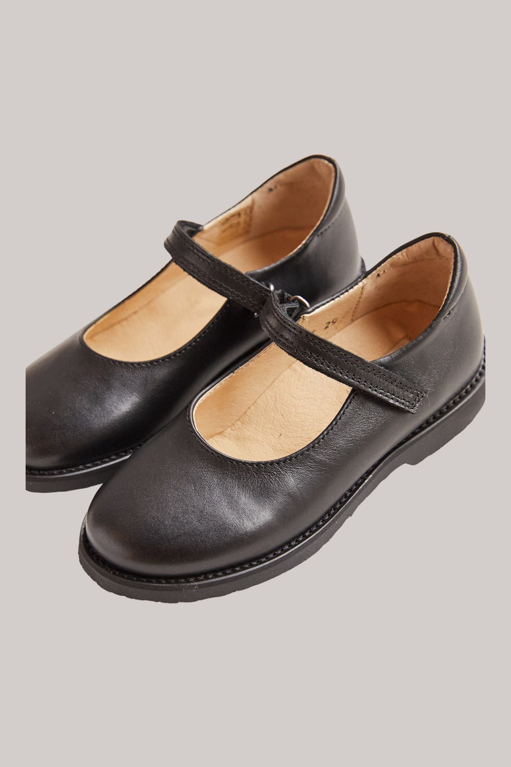 Papouelli - Emilia Strap Black - Strawberries & Cream - Ingrid Lewis - Designer
Pair of black leather shoes with a strap.