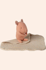 Pink hippo toy with a textured blanket on a white background