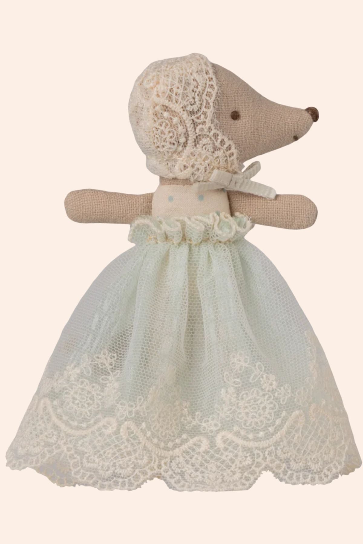 Stuffed animal toy wearing a lace dress and bonnet on a beige background